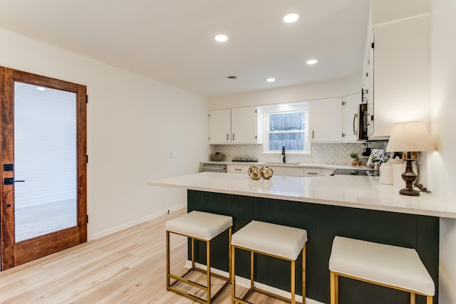 kitchen featuring sink, white cabinetry, range, kitchen peninsula, and decorative backsplash