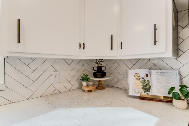 interior details featuring white cabinetry and light stone countertops