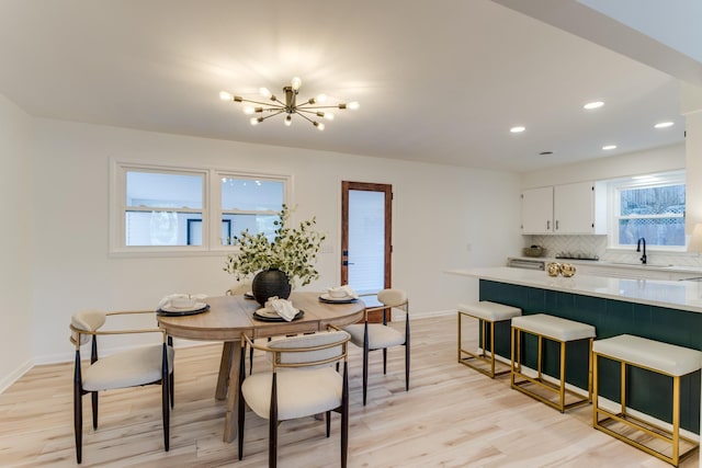 dining space featuring sink, a chandelier, and light wood-type flooring