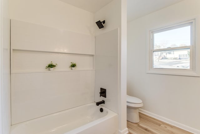 bathroom with hardwood / wood-style floors, toilet, and tiled shower / bath