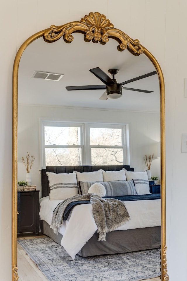 bedroom featuring hardwood / wood-style flooring, crown molding, and ceiling fan