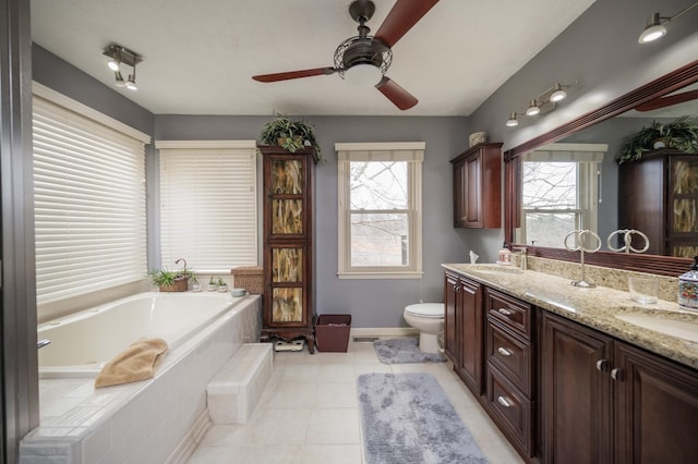 bathroom with vanity, a relaxing tiled tub, ceiling fan, toilet, and tile patterned floors