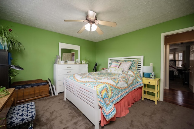 bedroom with ceiling fan, a textured ceiling, and dark colored carpet