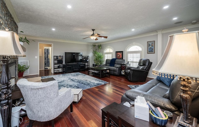 living room featuring a large fireplace, ornamental molding, ceiling fan, dark wood-type flooring, and a textured ceiling