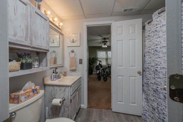 bathroom featuring toilet, a paneled ceiling, vanity, ceiling fan, and hardwood / wood-style floors