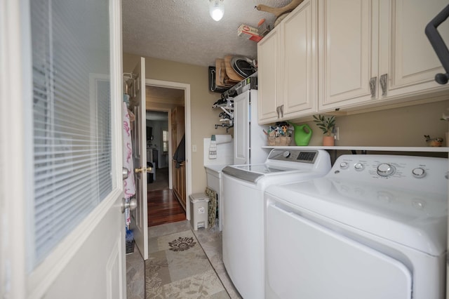 laundry area with cabinets, a textured ceiling, and washer and clothes dryer