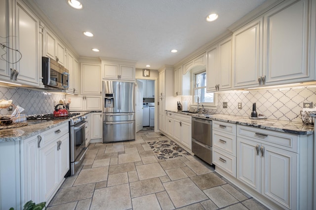 kitchen featuring white cabinetry, appliances with stainless steel finishes, and washer and dryer