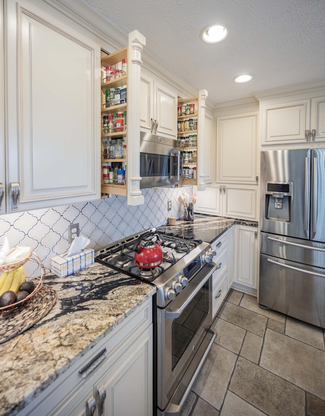 kitchen featuring white cabinetry, tasteful backsplash, a textured ceiling, appliances with stainless steel finishes, and light stone countertops