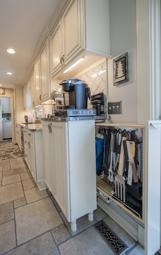 kitchen featuring dishwashing machine, light stone countertops, sink, and backsplash