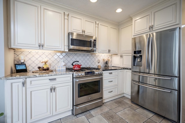 kitchen featuring light stone counters, backsplash, white cabinets, and appliances with stainless steel finishes