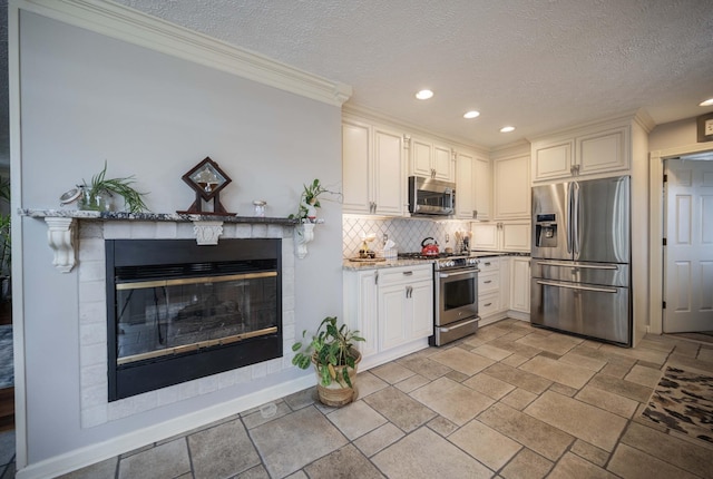 kitchen with appliances with stainless steel finishes, white cabinets, decorative backsplash, light stone counters, and kitchen peninsula