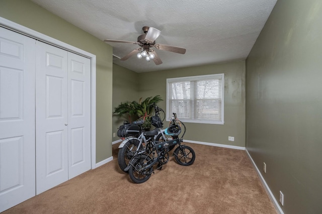 miscellaneous room featuring ceiling fan, light colored carpet, and a textured ceiling