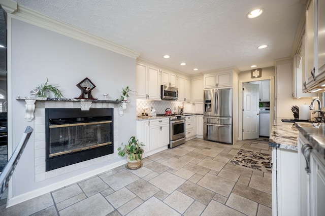 kitchen with stainless steel appliances, light stone countertops, sink, and white cabinets