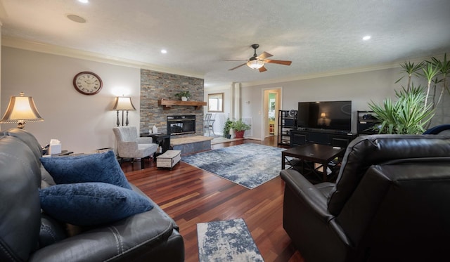 living room featuring hardwood / wood-style flooring, ceiling fan, a fireplace, ornamental molding, and a textured ceiling