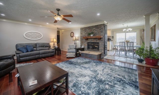 living room featuring ornamental molding, a stone fireplace, ceiling fan with notable chandelier, and dark hardwood / wood-style flooring