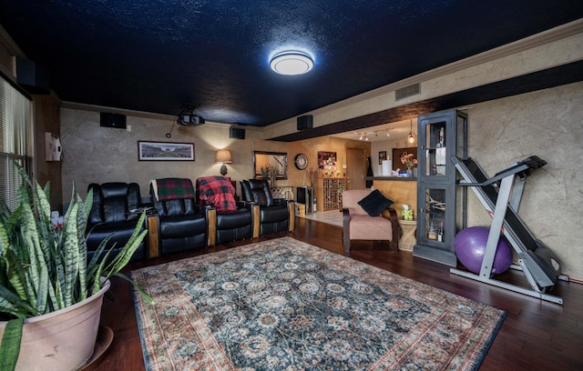 cinema room with crown molding, dark hardwood / wood-style floors, and a textured ceiling