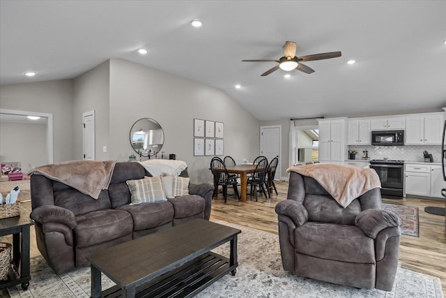 living room featuring ceiling fan, vaulted ceiling, and light hardwood / wood-style flooring