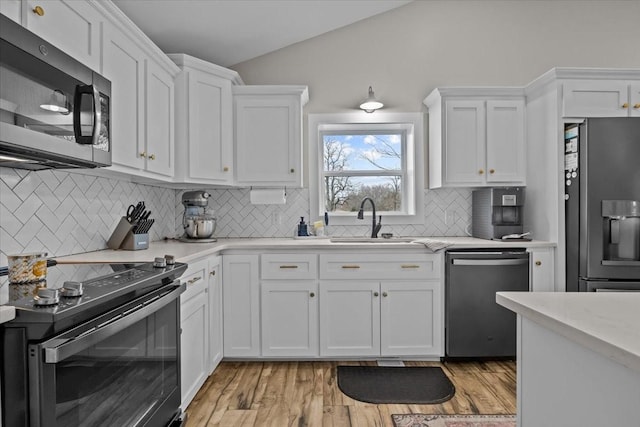 kitchen featuring white cabinetry, vaulted ceiling, and stainless steel appliances