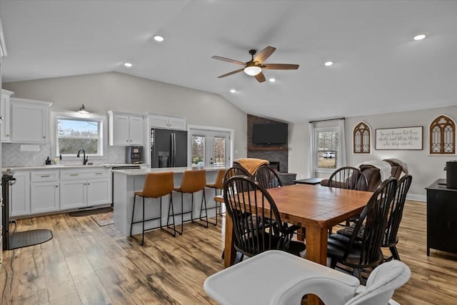 dining area with lofted ceiling, sink, and light hardwood / wood-style floors