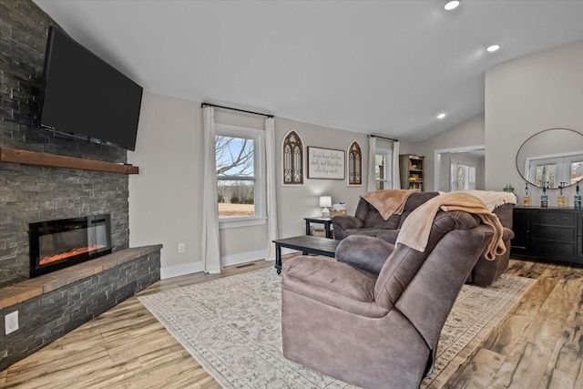 living room with light hardwood / wood-style flooring, a fireplace, and vaulted ceiling