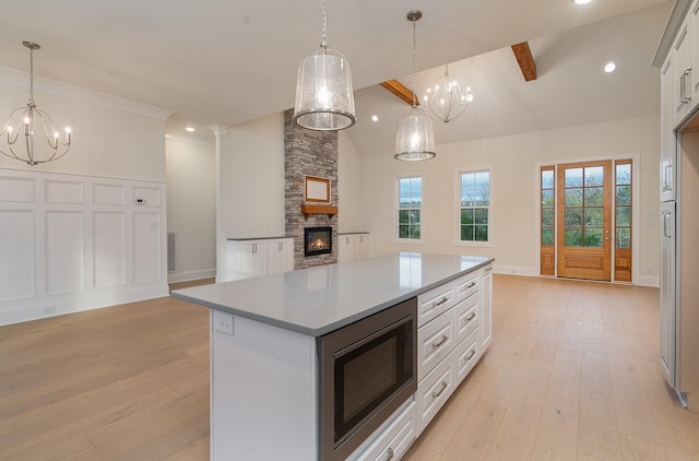 kitchen featuring built in microwave, pendant lighting, white cabinets, and a kitchen island