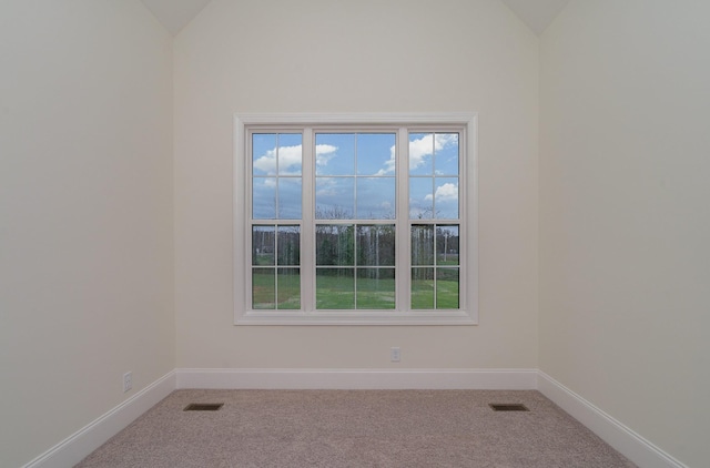 carpeted spare room featuring vaulted ceiling