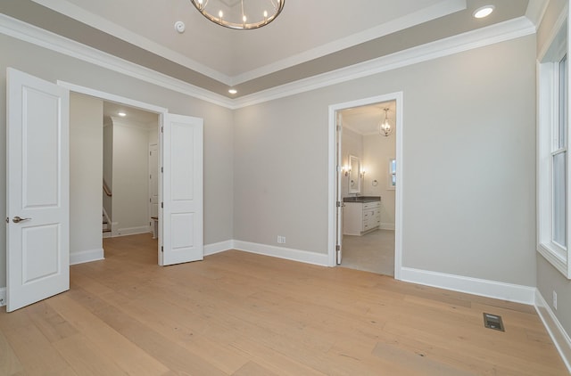 unfurnished bedroom featuring connected bathroom, crown molding, light hardwood / wood-style floors, and a chandelier