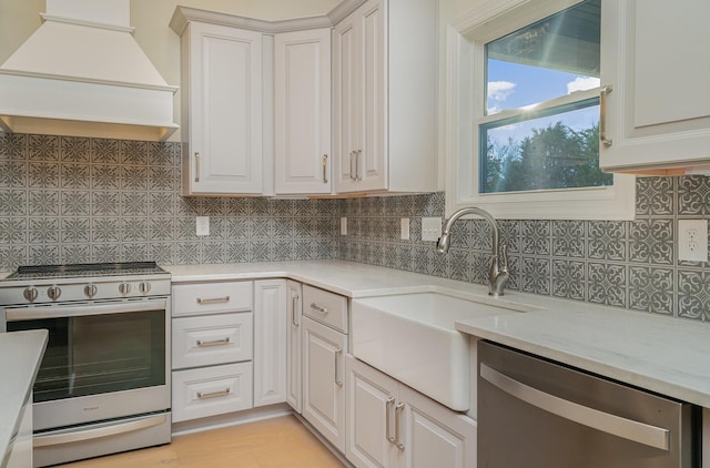 kitchen featuring white cabinetry, sink, stainless steel appliances, and premium range hood