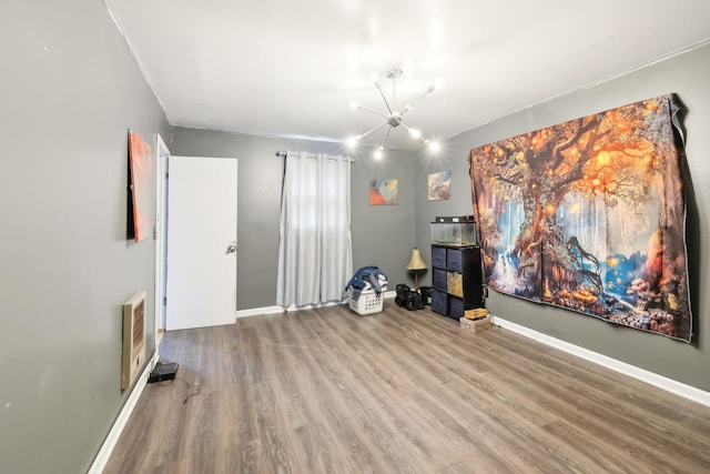 miscellaneous room featuring wood-type flooring, heating unit, and a notable chandelier