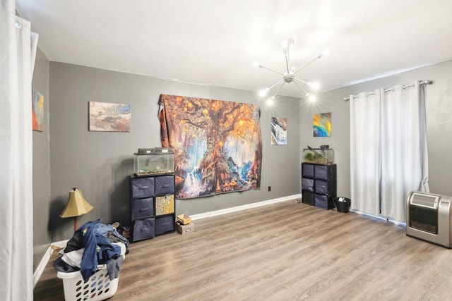 misc room featuring hardwood / wood-style flooring, heating unit, and a notable chandelier