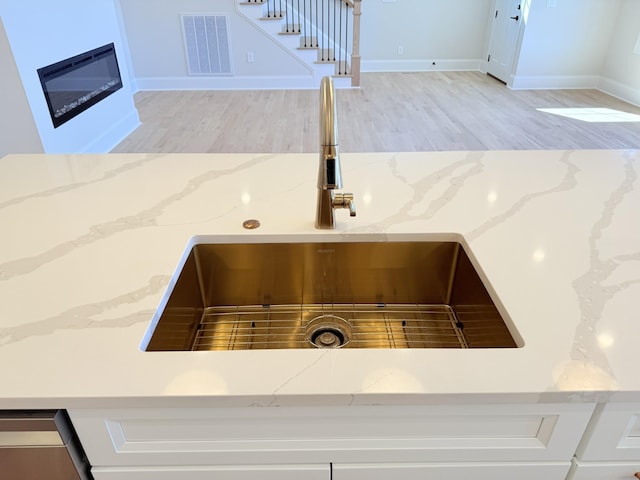 details featuring light stone counters, sink, and hardwood / wood-style flooring