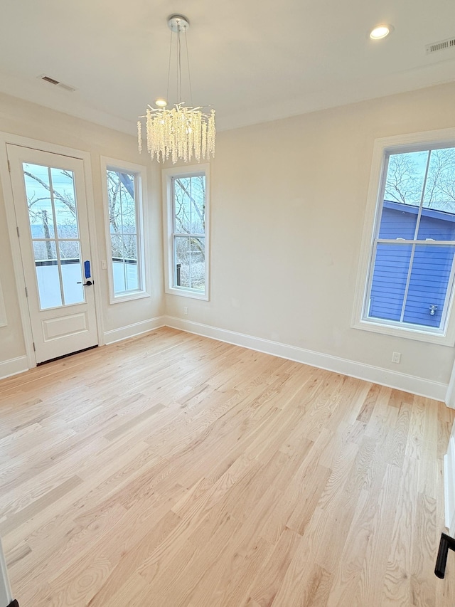 unfurnished dining area featuring light hardwood / wood-style flooring and a notable chandelier