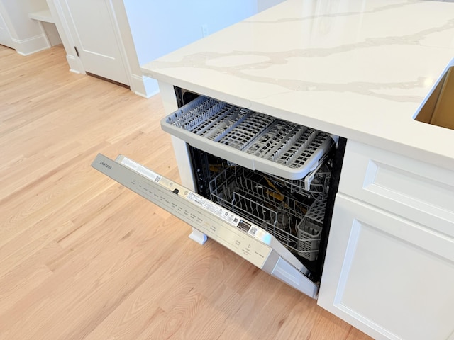 room details featuring light stone counters, white cabinetry, and light hardwood / wood-style floors