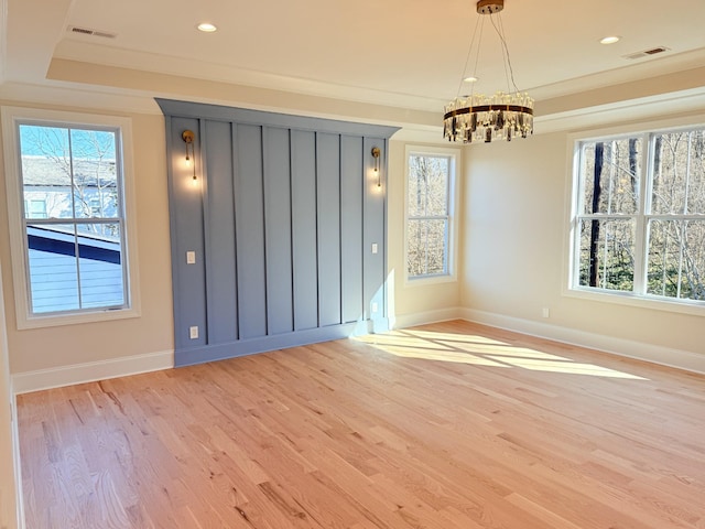 empty room featuring crown molding, a chandelier, and light wood-type flooring