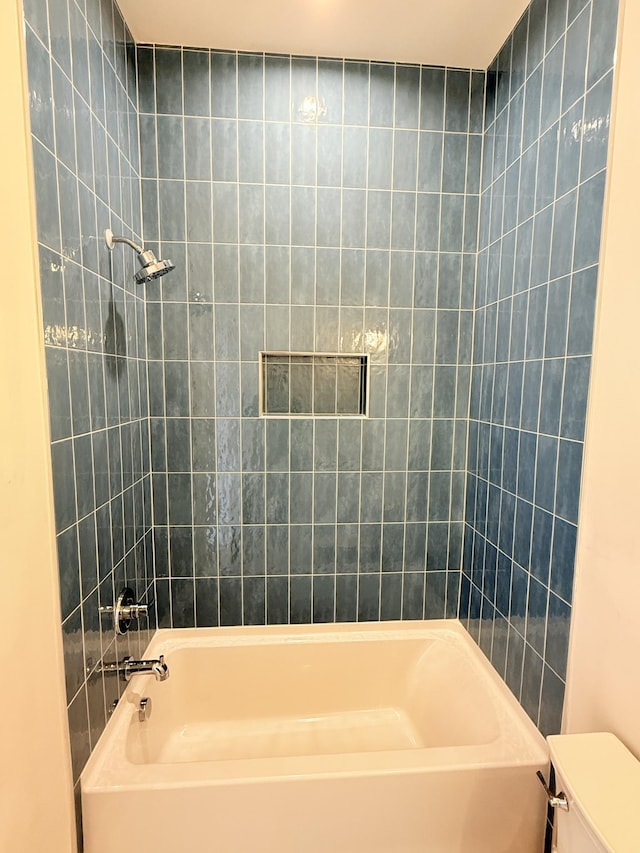 bathroom featuring tiled shower / bath and toilet