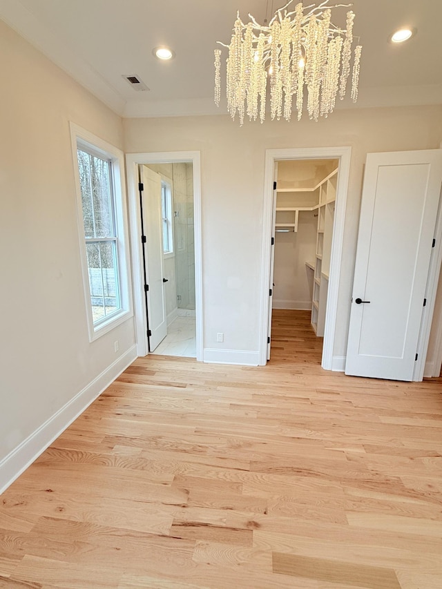 unfurnished bedroom featuring a closet, a walk in closet, ensuite bath, and light hardwood / wood-style flooring