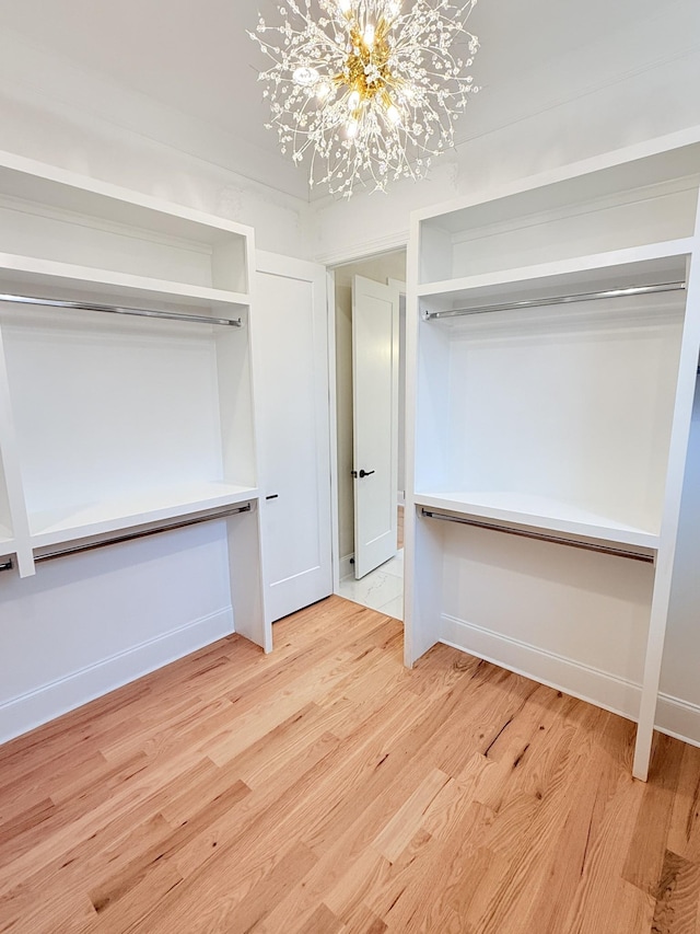 walk in closet with a notable chandelier and light hardwood / wood-style floors