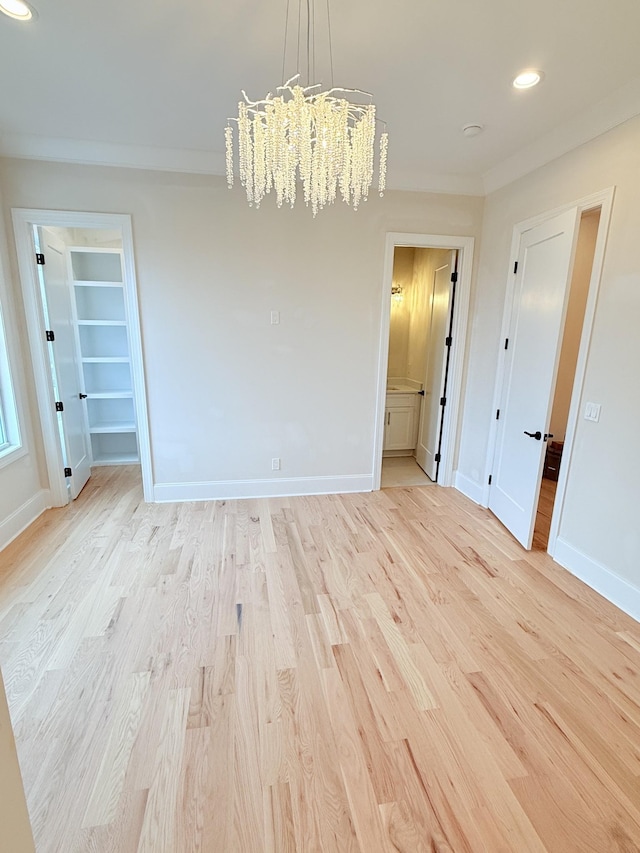 empty room with a notable chandelier and light wood-type flooring