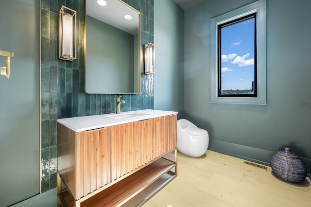 bathroom featuring vanity, hardwood / wood-style flooring, tile walls, and toilet