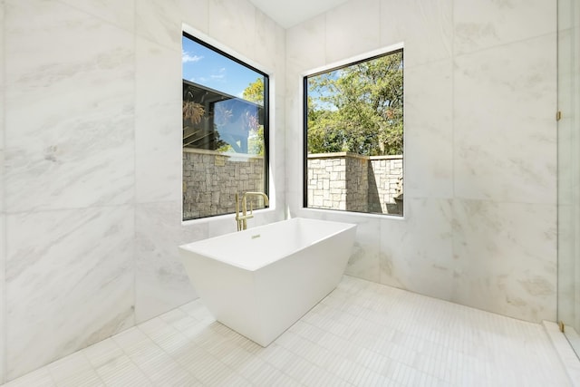 bathroom with a bathing tub and tile walls