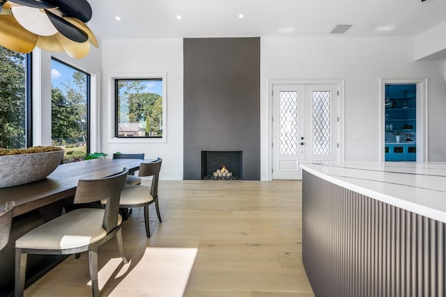 dining room with a wealth of natural light, light wood-type flooring, and french doors