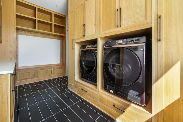 laundry area featuring cabinets, washing machine and clothes dryer, and dark tile patterned flooring