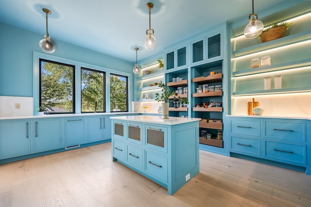 kitchen with blue cabinets, a center island, pendant lighting, and light hardwood / wood-style flooring