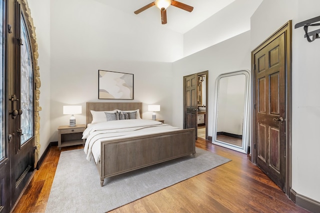 bedroom with dark hardwood / wood-style flooring, ensuite bath, ceiling fan, and a high ceiling