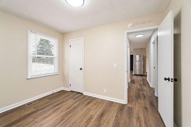 interior space with dark wood-type flooring, stainless steel refrigerator, and a textured ceiling