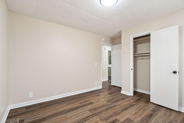 unfurnished bedroom featuring dark wood-type flooring, a closet, and a textured ceiling