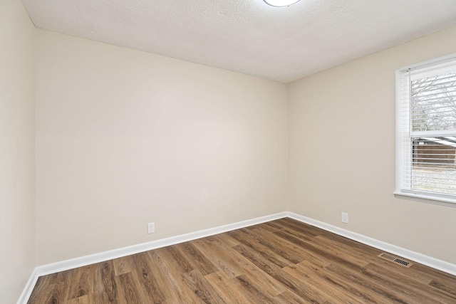 unfurnished room featuring wood-type flooring and a textured ceiling