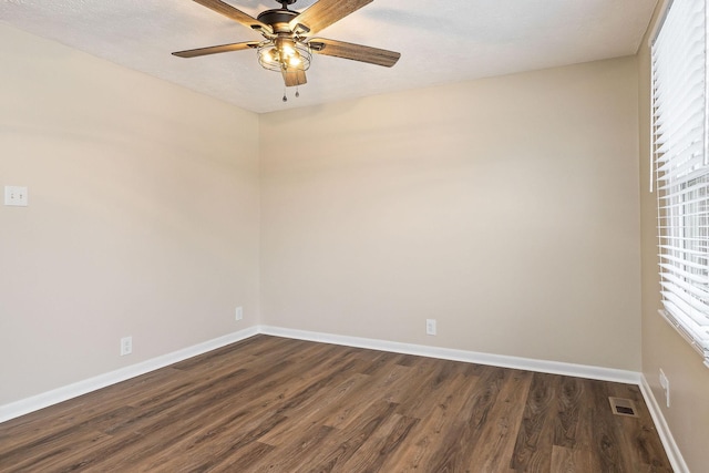 empty room with a wealth of natural light, dark hardwood / wood-style floors, and ceiling fan