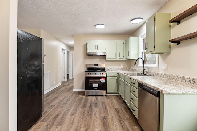 kitchen with dark wood-type flooring, sink, green cabinetry, a textured ceiling, and stainless steel appliances