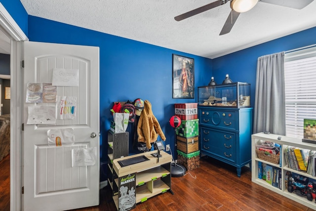 rec room featuring ceiling fan, a textured ceiling, and dark hardwood / wood-style flooring